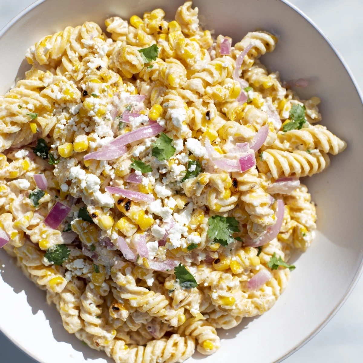 Bright and creamy Creamy Street Corn Pasta Salad topped with cotija cheese, ready to be served.
