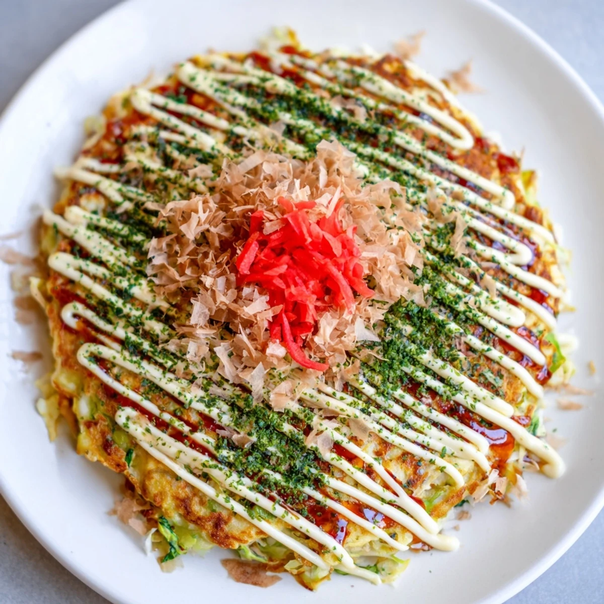 A close-up view of a delicious Okonomiyaki pancake, with visible cabbage and savory toppings ready to eat.