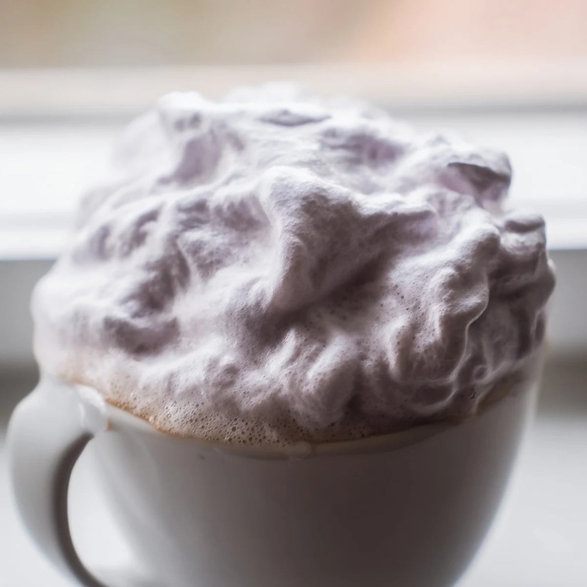 Enjoy a relaxing afternoon with this creamy Whipped Lavender Latte, topped with fluffy foam and served beside a buttery scone.