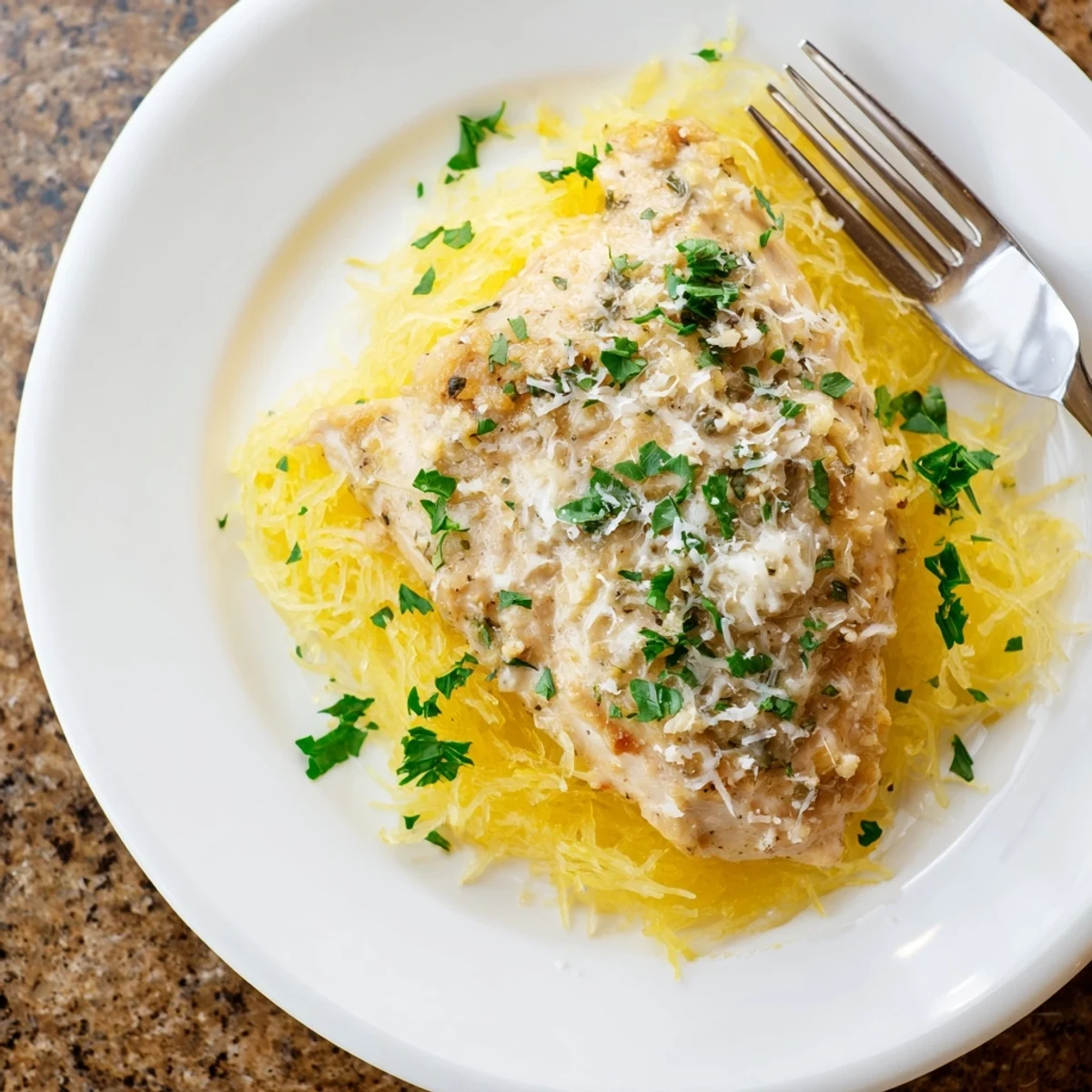 A close-up of the vibrant Lemon Garlic Chicken Spaghetti Squash, featuring zesty pan sauce and fresh herbs for garnish.
