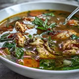 Healthy Turmeric Chicken Soup served in a rustic bowl, showing tender chicken and spinach.