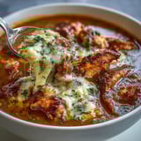 Colorful Grilled Chicken Parmesan Soup simmers in a rustic pot, featuring grilled chicken chunks, tomatoes, herbs, and vegetables.  