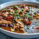 Southwestern Turkey Soup garnished with fresh cilantro, creamy avocado slices, and crushed tortilla chips for a crunchy Tex-Mex finish.  