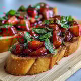 Fresh strawberry bruschetta with balsamic glaze and mint on toasted baguette slices, perfect for summer entertaining.
