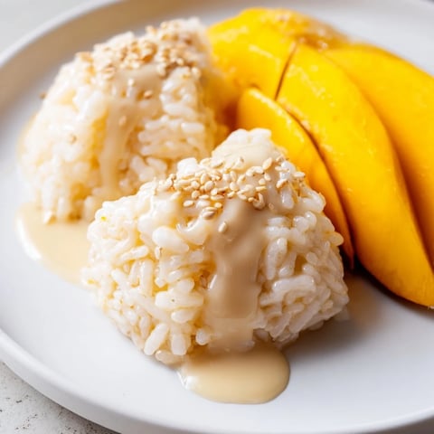 Golden slices of mango alongside a mound of creamy Thai Mango Sticky Rice, ready to savor.