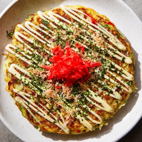 Golden, crispy Japanese Okonomiyaki pancake, served hot and topped with savory sauce and bonito flakes.