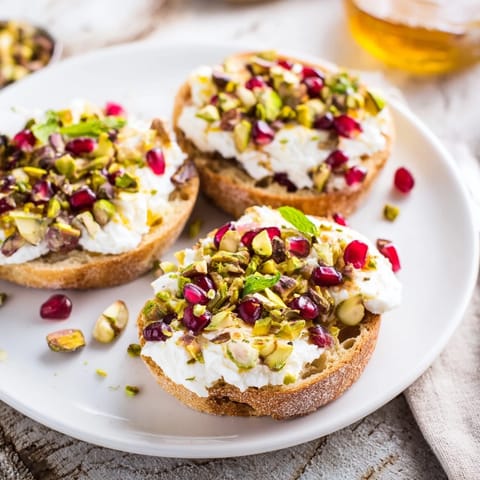 Creamy goat cheese spread over crispy crostini, then generously adorned with pomegranate in this appetizer.