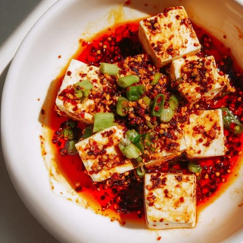 Savory and spicy Mapo Tofu simmering, with red chile oil, served atop fluffy, steamed rice.