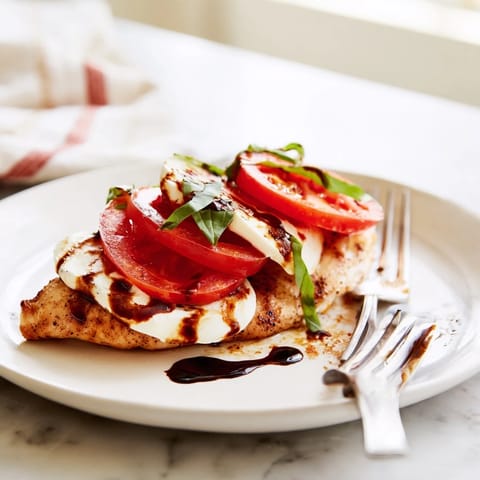 Caprese Chicken Skillet in a rustic pan, featuring juicy chicken breasts covered in creamy mozzarella and vibrant tomato slices.