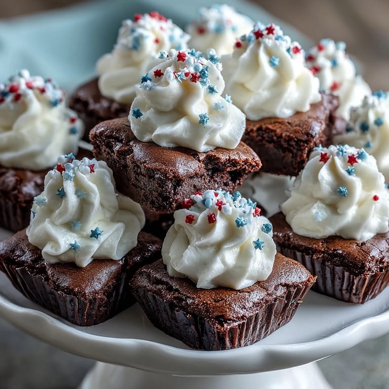 Decadent brownie bites topped with cream cheese frosting and festive sprinkles, ideal for July 4th parties.