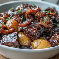 A hearty Japanese Nikujaga stew with tender beef, potatoes, and onions in a sweet-savory soy broth, served steaming hot.  