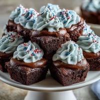 Rich 4th of July Firecracker Brownie Bites with red, white, and blue sprinkles on creamy vanilla frosting.  