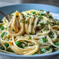 Bright spring pasta with creamy ricotta, lemon zest, and sweet peas tossed with linguine for a light vegetarian dinner.